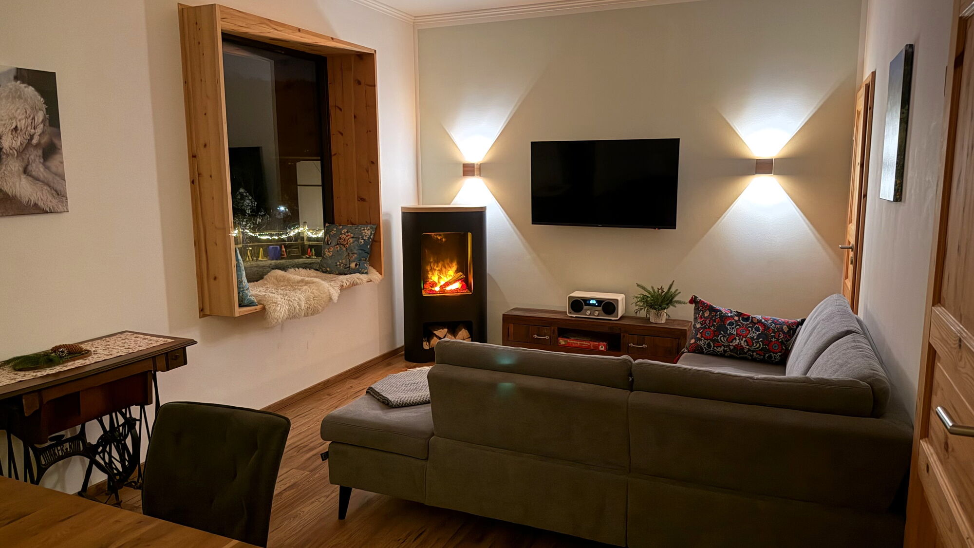 Das Wohnzimmer mit dem stimmungsvollen Flammenspiel des Elektrokamins im Ferienhaus Landchalet Eifel auf dem Landgut Pfauenhof in der Eifel.